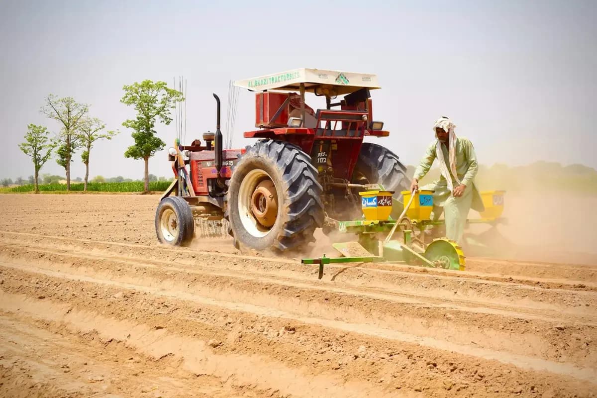 Farmer walking beside a tractor and multi-bed planter working in a field in Bahawalpur, Pakistan